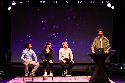 paneldiscussie op podium met sprekers en presentator