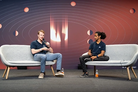 interview op podium tijdens technologie conferentie met twee sprekers